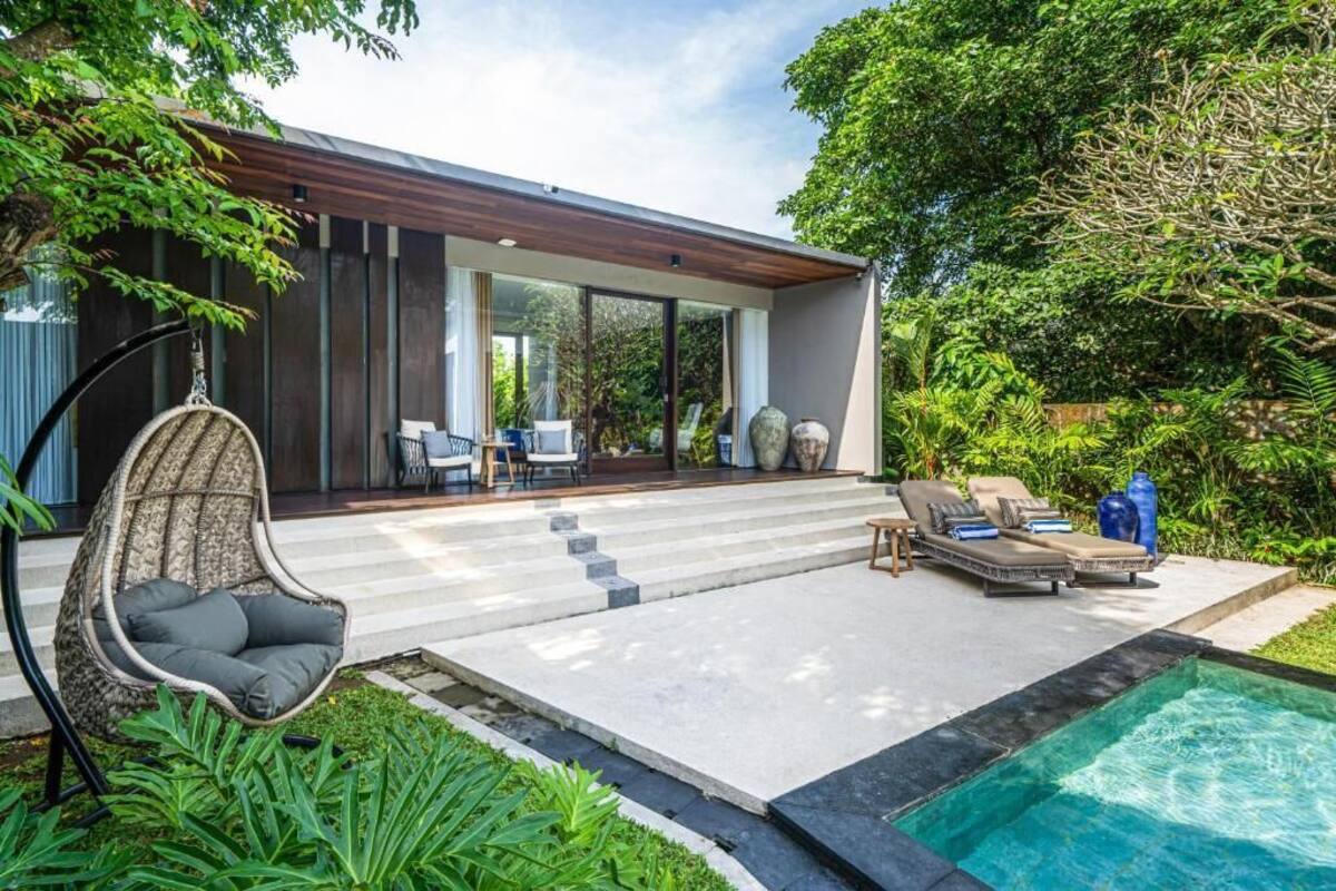 A modern house with a swimming pool, outdoor seating, and lush greenery.