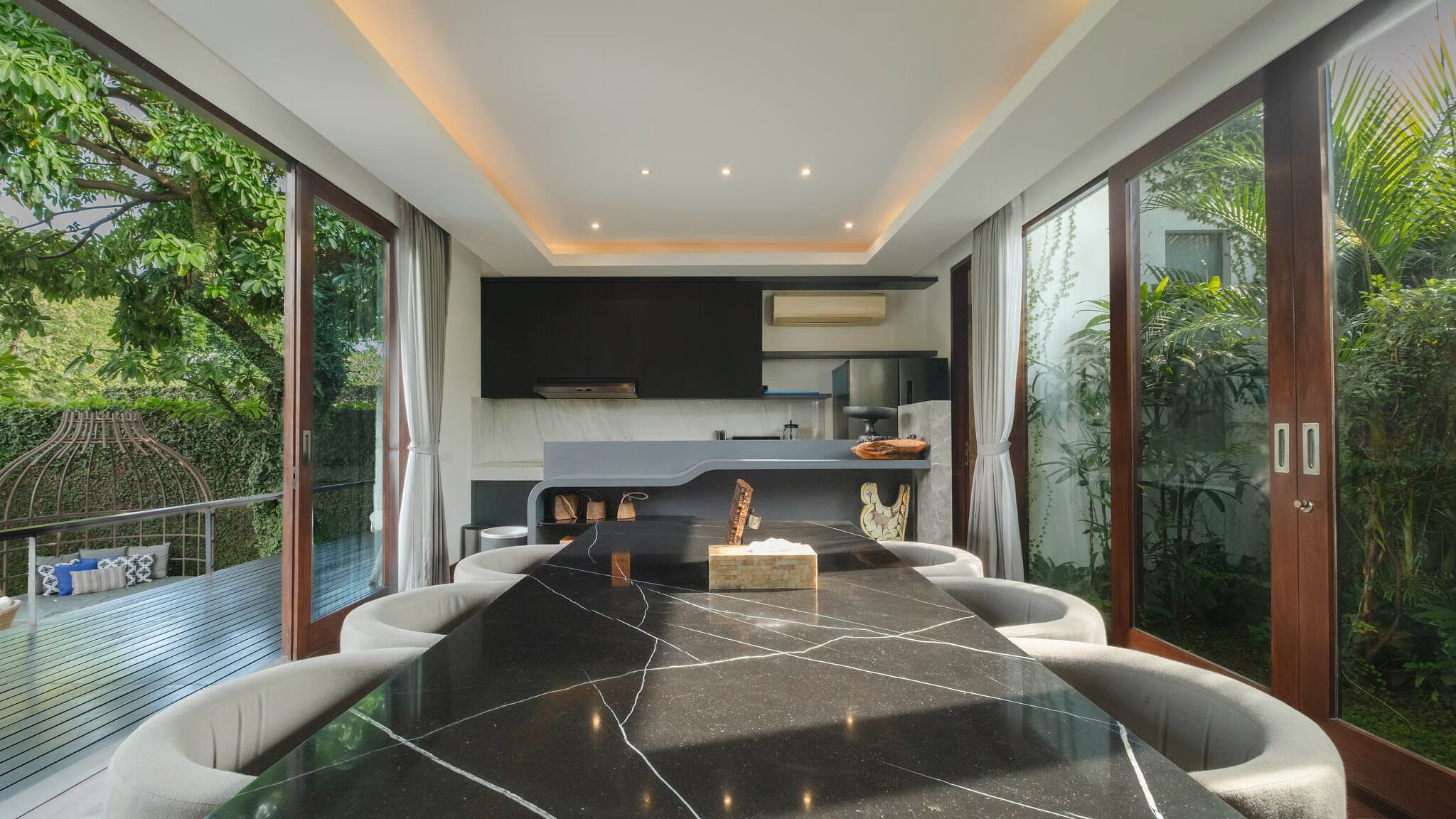 A modern kitchen with a black marble countertop, a built-in oven, and a large window overlooking a lush garden.