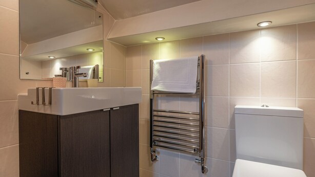 Une salle de bain moderne avec un meuble-lavabo, un porte-serviettes et des toilettes.