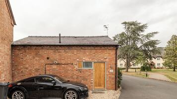 A black car parked in front of a brick building with a wooden door and a small window.