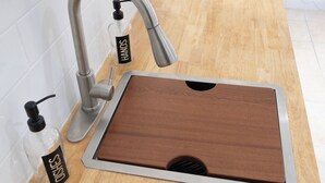 A modern kitchen with a stainless steel faucet, a wooden countertop, and a small soap dispenser.