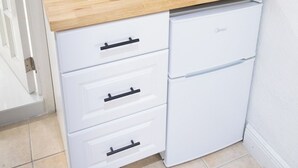 A compact kitchen with a wooden countertop, a built-in stove, and white cabinetry.