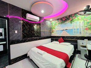 A modern bedroom with a large bed, a small desk, and a wall mural of a seaside scene. - T&T Hotel (Ho Chi Minh City)