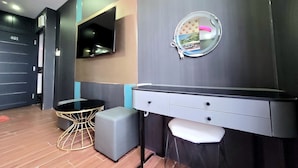 Une salle de bain moderne avec un meuble-lavabo, un miroir rond, un téléviseur et un petit tabouret.