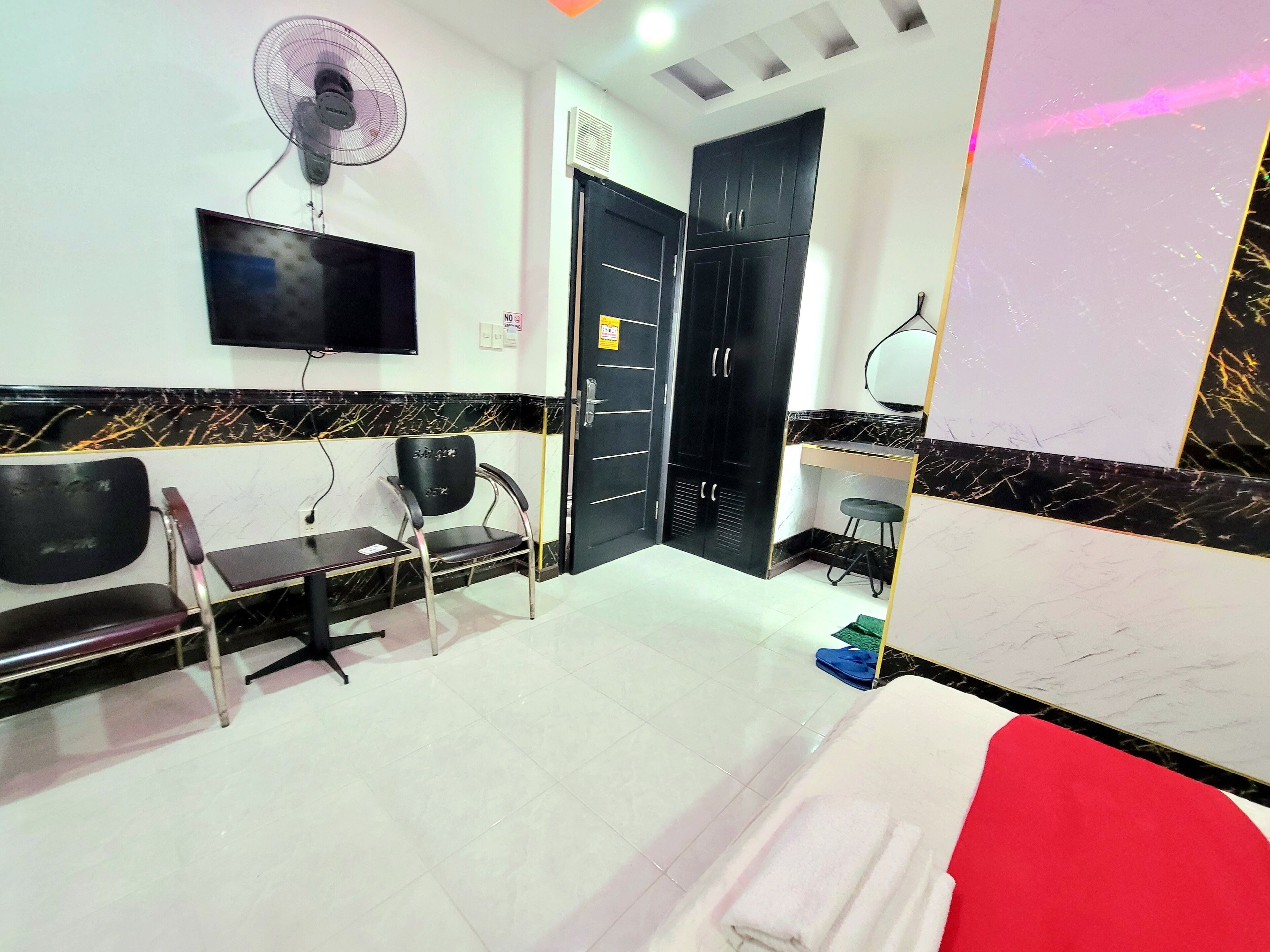 A hotel room with a bed, a TV, a fan, a desk, and a wardrobe.