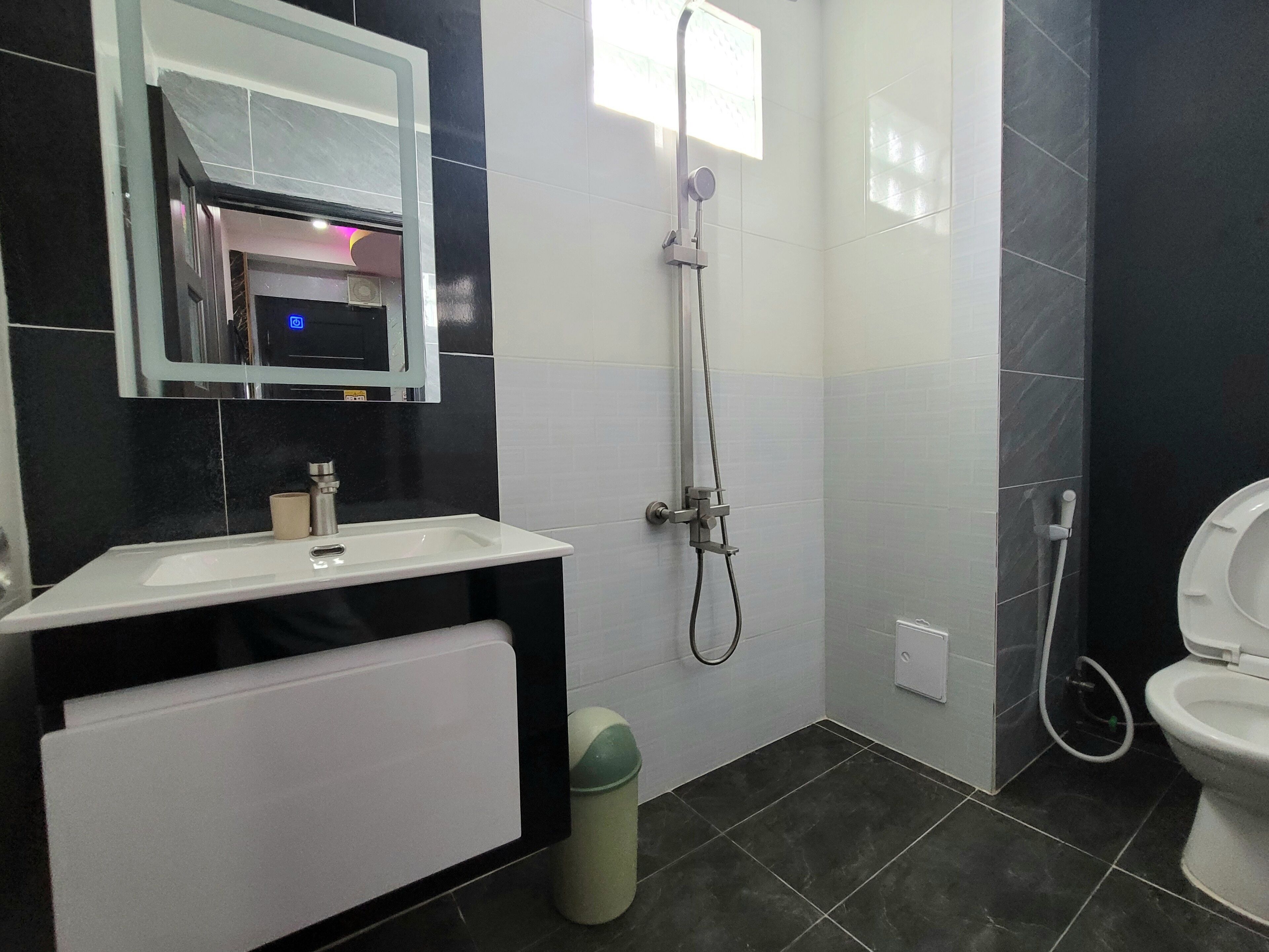 A bathroom with a white sink, a mirror, a shower, and a toilet.
