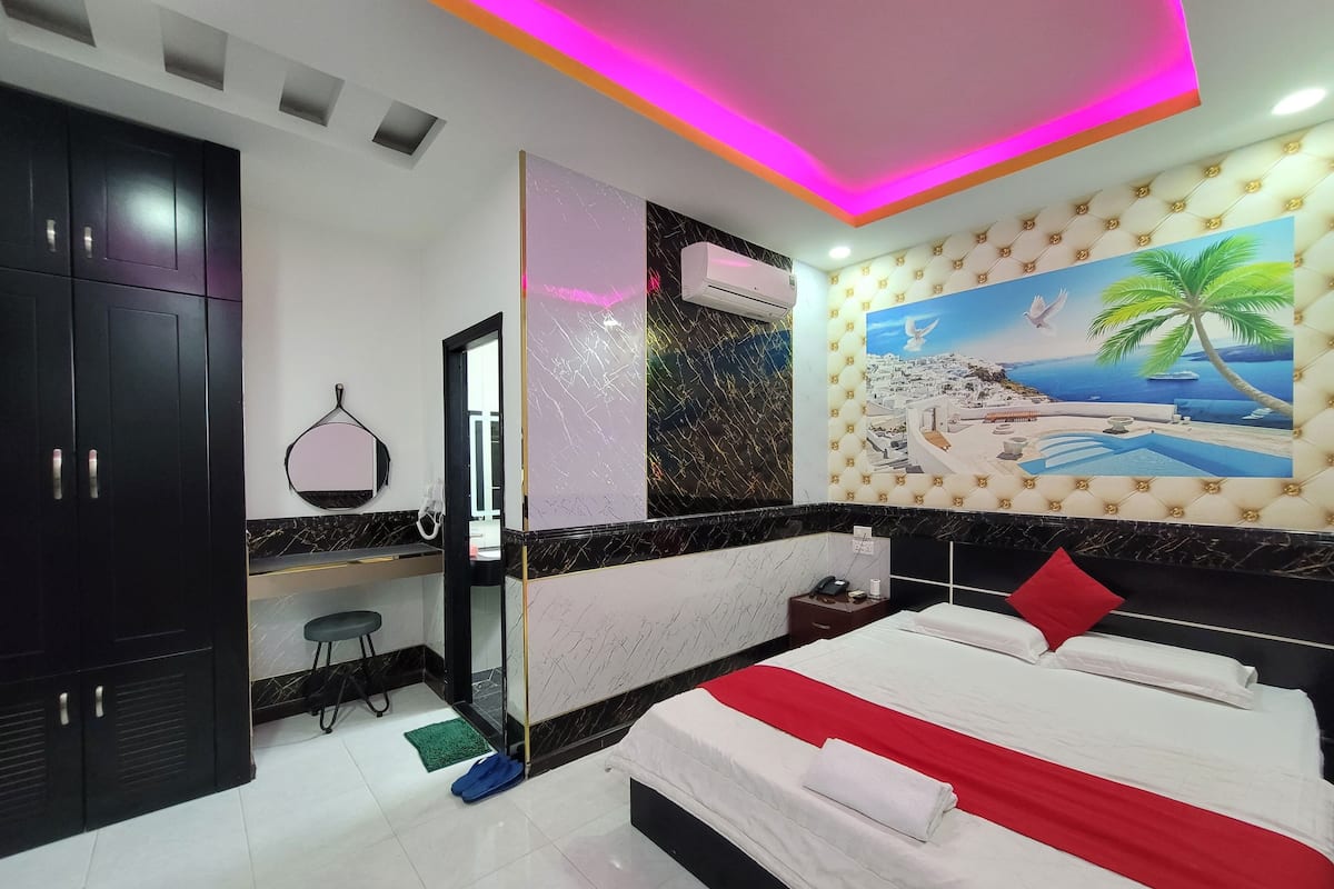 Una habitación de hotel con una cama, un escritorio, un armario y un cuadro de una playa.