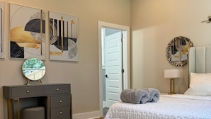 Un dormitorio con cama, banco, cómoda y obras de arte en la pared.