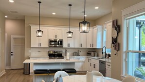 Una cocina moderna con armarios blancos, una isla central e iluminación colgante.