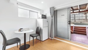 Una cocina compacta con refrigerador, microondas y un pequeño comedor con dos sillas.