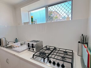 A modern kitchen with a gas stove, a toaster, and a window with a view of a building.