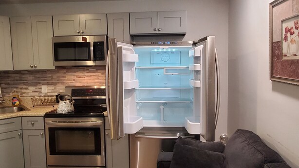 A compact kitchen with a stainless steel refrigerator, oven, and microwave.