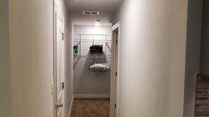 A narrow hallway with wooden flooring, white walls, and a built-in shelf unit with folded towels.