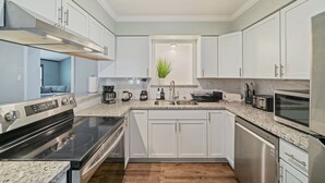 A modern kitchen with white cabinets, stainless steel appliances, granite countertops, and a built-in oven. - Amazing 4BR 2Bath Home with Pool & Game-Movie Room (Texas City)