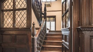 A wooden staircase with ornate railings and a view of a room with a window and a painting. - Severn End - 15th Century Manor House (Worcester)