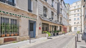 A street with buildings, a blue door, and potted plants.