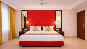 Camera d'albergo moderna con un letto grande, testiera rossa e uno specchio sopra il letto.