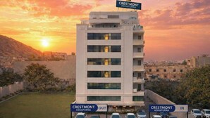 Un edificio a più piani con un cartello che riporta “Crestmont Ashapura” sulla sommità. Sono presenti due segnali di parcheggio, uno recante “Crestmont Ashapura Out” e l’altro “Crestmont Ashapura In”. 