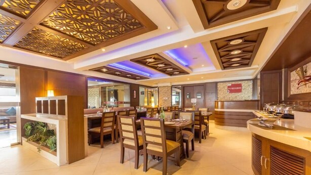 A restaurant with wooden furniture, a bar area, and a decorative ceiling. - Crestmont Ashapurna Jaipur  (Jaipur)