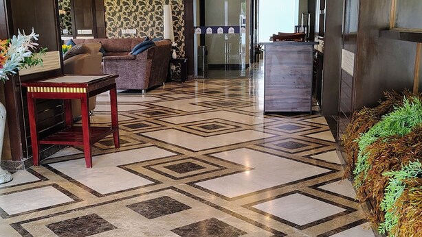 Un'hall d'albergo con pavimento decorato, zona salotto e reception.