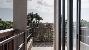 A balcony with a view of the sky and trees, featuring a wooden railing and a tiled floor.