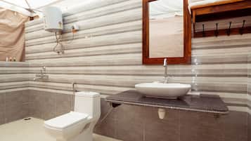 Une salle de bain avec des toilettes blanches, un lavabo et une douche.