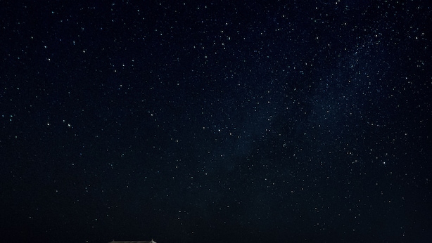 Une rangée de tentes blanches, avec un ciel nocturne dégagé au-dessus.