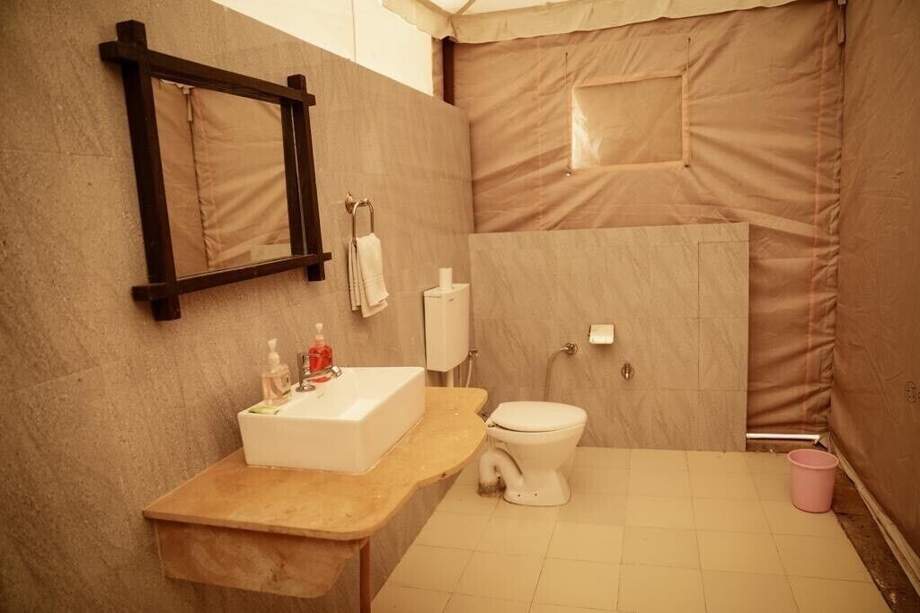 Un baño con tocador de madera, un lavabo blanco, inodoro y espejo.