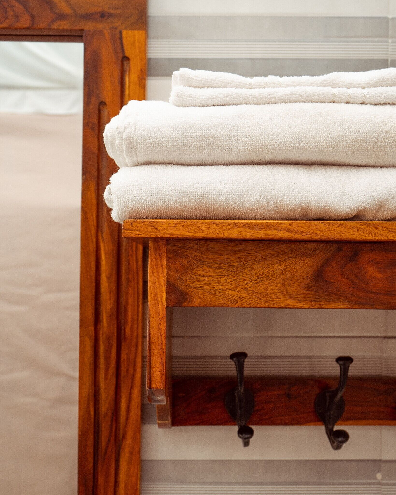 A wooden shelf with folded white towels.