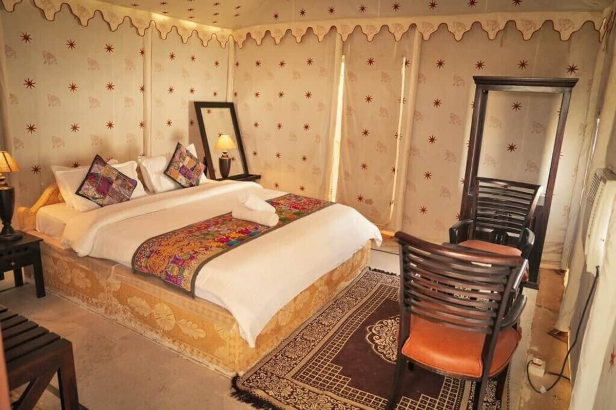 A neatly arranged hotel room with a large bed, a chair, a nightstand, and a mirror.