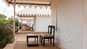 Un espace extérieur aménagé avec une tente, des tables et des chaises, un chemin et de la verdure.