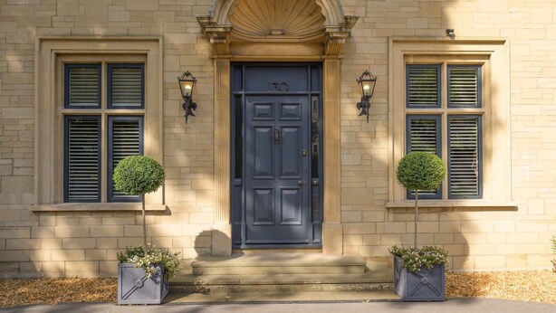 A building with a dark blue door, numbered 130, flanked by two windows with shutters. - Luxurious Home in Cheltenham, Private Parking (Gloucestershire)