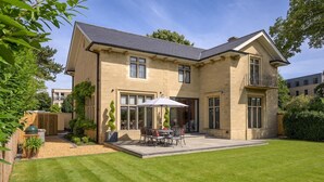 A two-story house with a patio, a barbecue grill, and a well-maintained lawn. - Luxurious Home in Cheltenham, Private Parking (Gloucestershire)