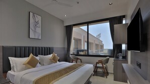 Une chambre d’hôtel moderne dotée d’un grand lit, d’une télévision à écran plat, d’un bureau et offrant une vue sur le bâtiment situé à l’extérieur.