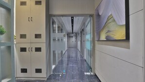 Un couloir avec des casiers, une porte vitrée et une œuvre d’art accrochée au mur.