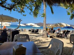 A beach with sun loungers, umbrellas, and a clear view of the sea.