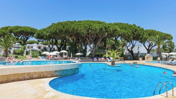 A pool area with multiple swimming pools, lounge chairs, and umbrellas.