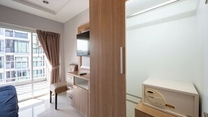 A modern hotel room with a large window, a desk with a flat-screen TV, a microwave, and a wardrobe. - New Nordic Trend 3 (Pattaya)