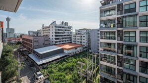 A multi-story building with balconies and large windows, surrounded by other buildings and greenery. - New Nordic Trend 3 (Pattaya)