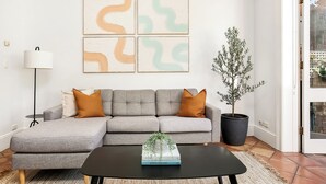 Un salon avec un canapé d’angle gris, une table basse noire et une plante en pot.