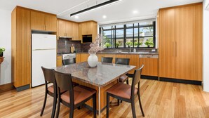 A modern kitchen with wooden cabinets, a granite countertop, and a dining area with chairs. - Balmain Retreat - 2BR + Study (Inner West Council)
