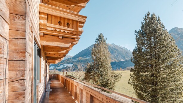 A wooden balcony with a view of mountains and trees. - Beautiful apartment for 4 people with TV and balcony (Neukirchen Am Großvenediger)