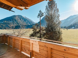 Una terraza de madera con vistas a un paisaje montañoso.