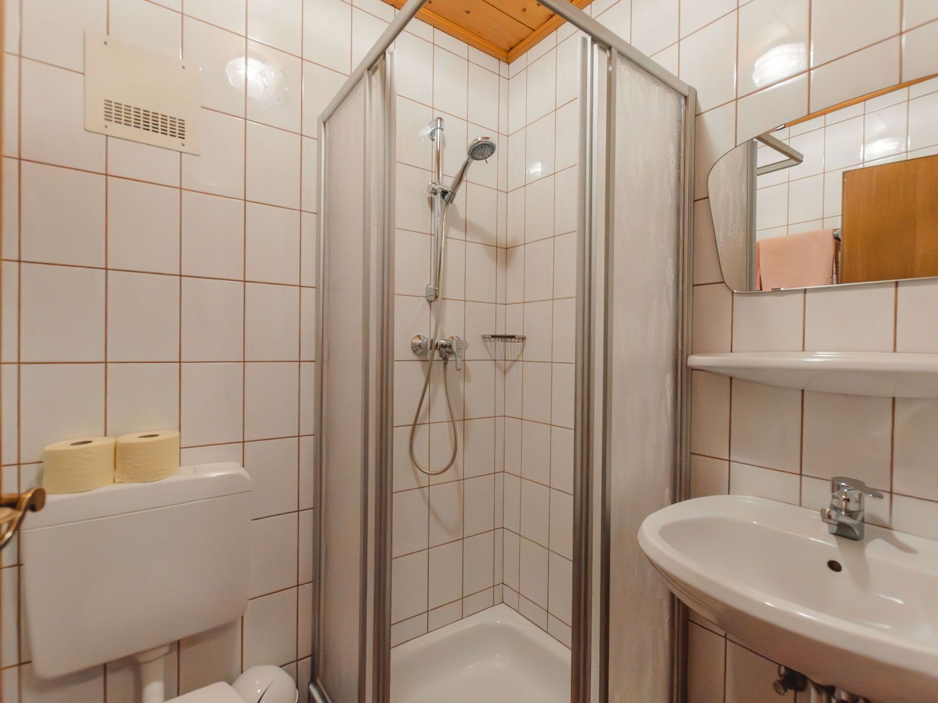 Un bagno con doccia vetro, lavandino e WC.
