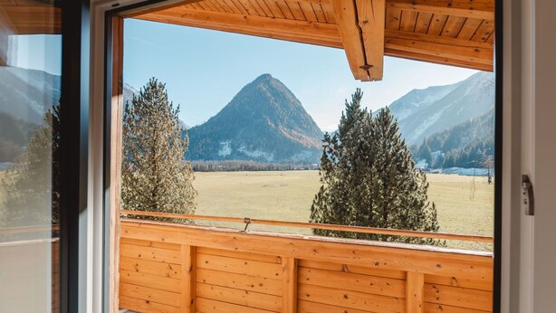 Un balcón de madera con vistas a una montaña y árboles.