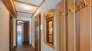 Un pasillo con puertas de madera, un interruptor de luz y un teléfono.