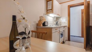 Una cocina con armarios blancos, encimera de madera y una mesa de comedor con una botella y cristalería.