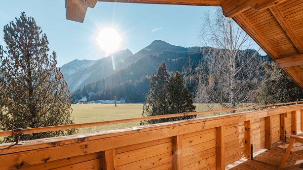 A wooden deck with a view of mountains and a clear sky.