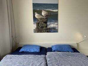 Cozy retreat with a single bed and a framed ocean view above.