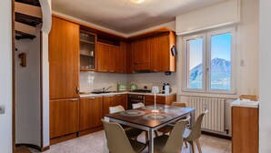 Une cuisine compacte avec des meubles en bois, une table à manger avec des chaises et une vue sur une montagne par la fenêtre.